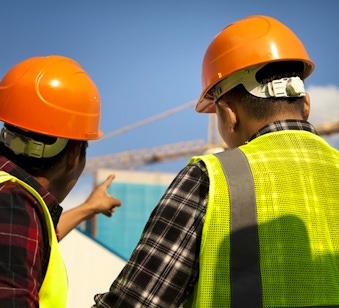 Two construction workers pointing towards a crane